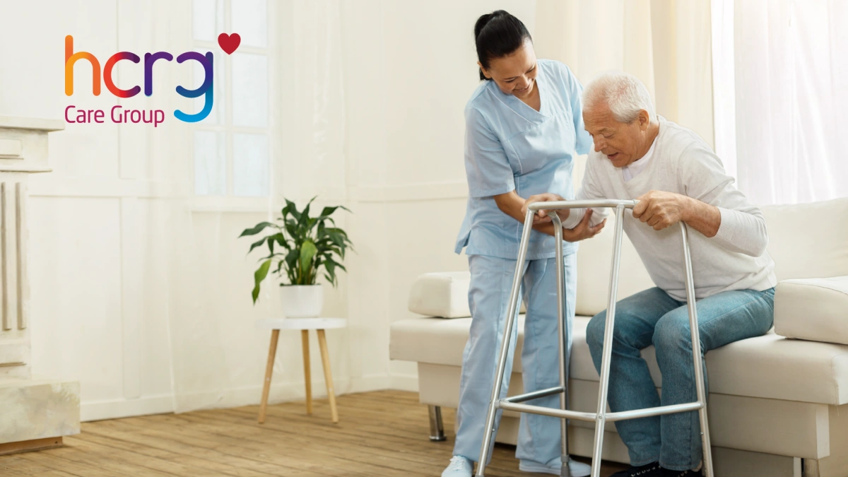 A nurse assisting a man with a walking aid, overlayed with the HCRG care group logo.