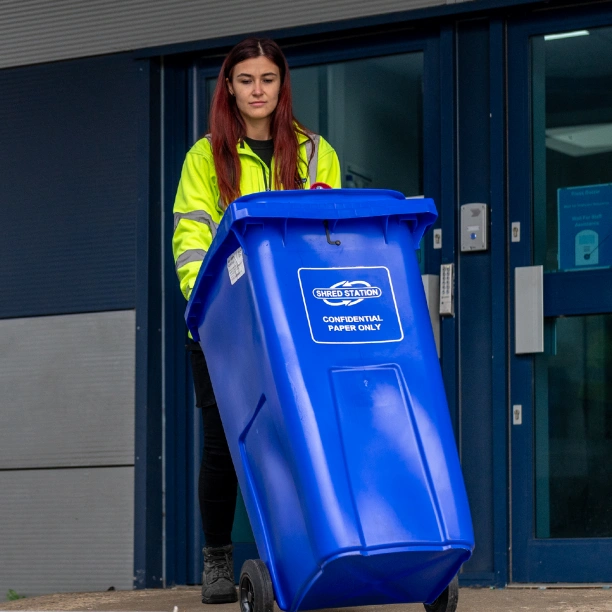 Shred Station operative pushing a blue 240-litre confidential waste bin.