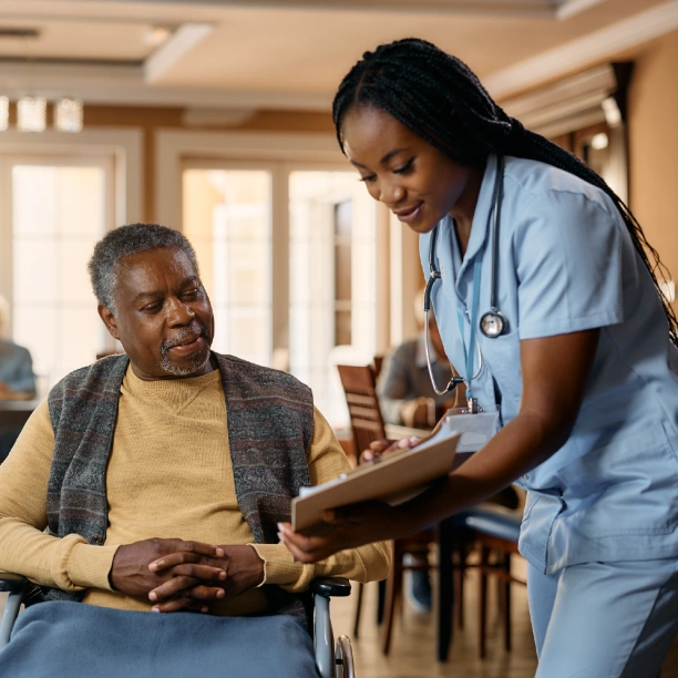 A doctor showing a patient in a wheelchair some paperwork.