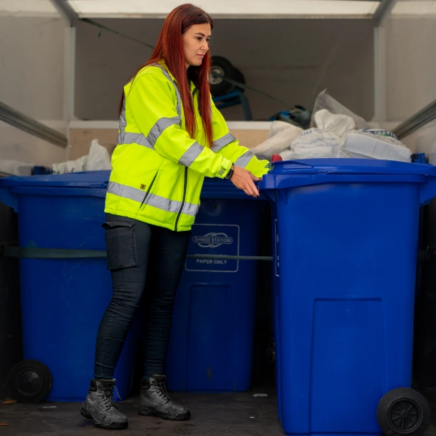 A Shred Station operative inside an off-site shredding collection vehicle, surrounded by blue confidential waste bins.