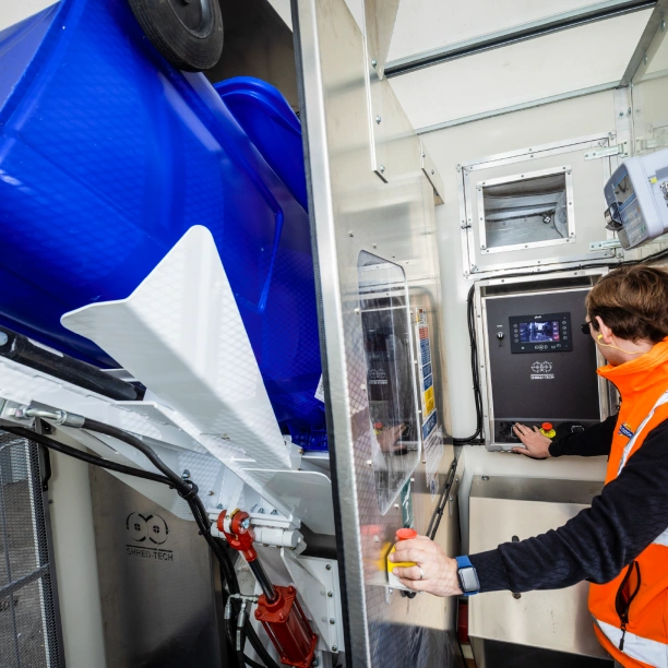 A Shred Station operative tipping a confidential waste bin into an on-site industrial shredding truck's on board shredding machine.