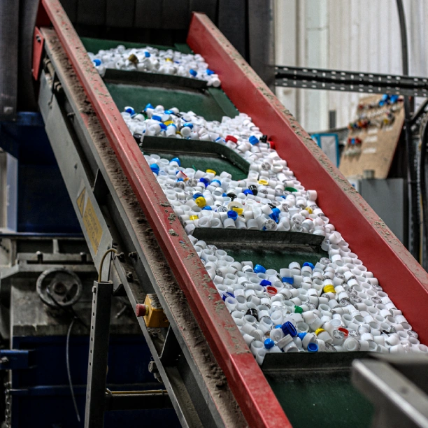 Plastic bottle caps entering an industrial plastic granulation machine.