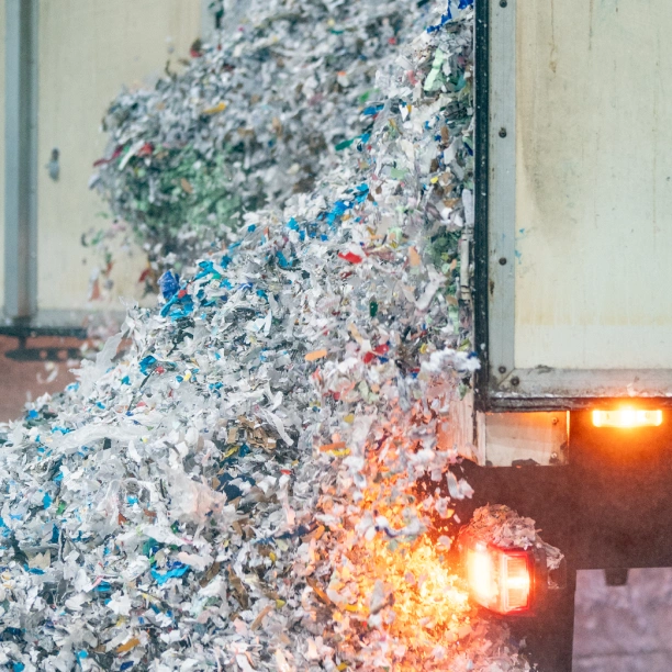 Shredded paper exiting the back of an on-site shredding vehicle
