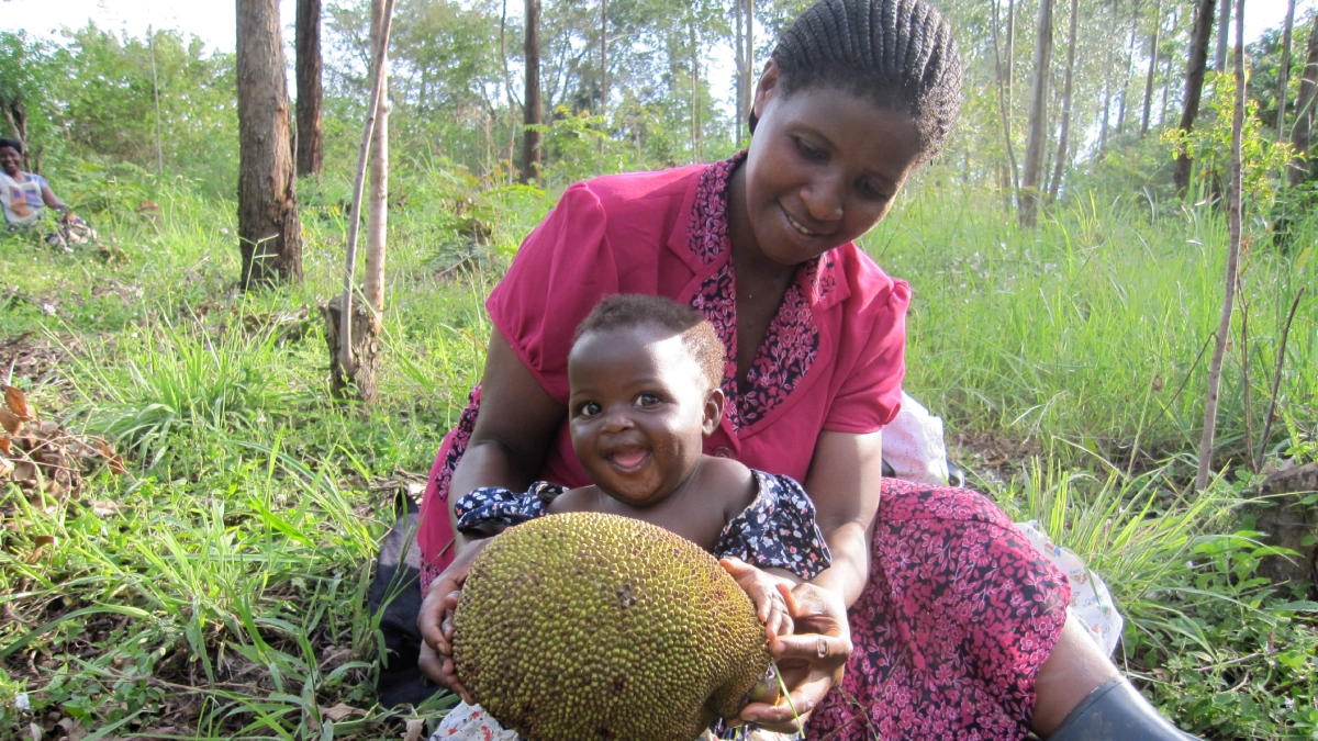 A mother and her daughter collecting fruit in the Uganda Community Reforestation project area.