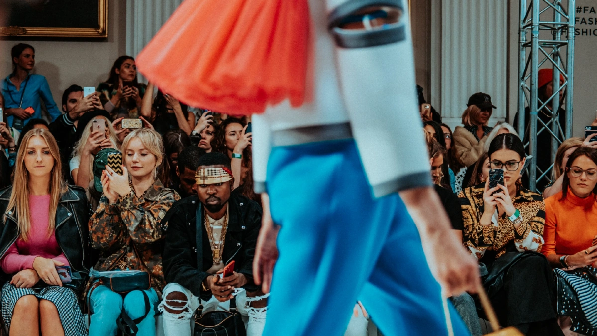 Fashion show, with audience taking photographs of a model as they walk down the runway.