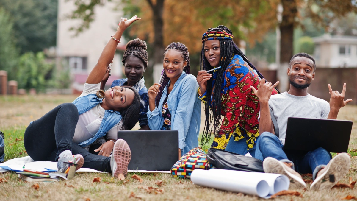 Five university students studying outside on the grass.