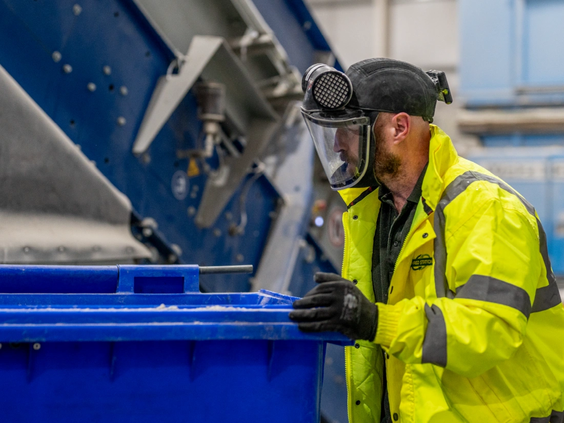Shred Station operative pushing large blue waste bin in full PPE.