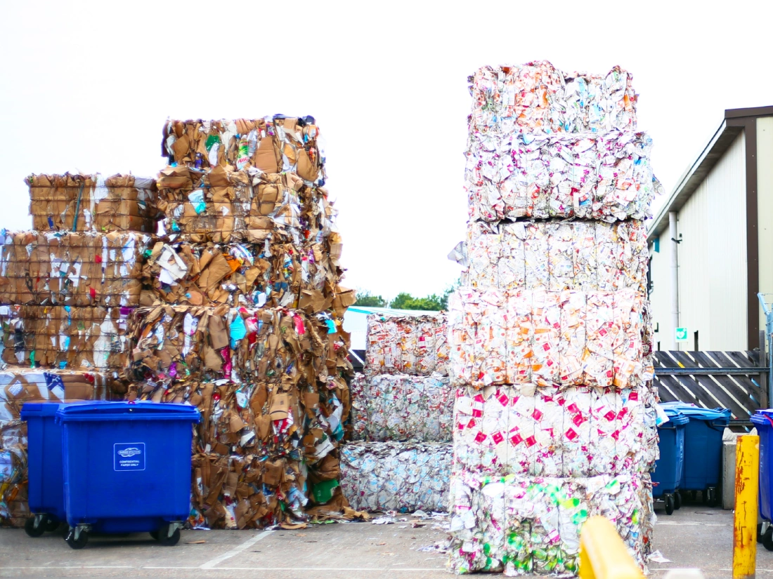 Bales of cardboard and Tetra Paks in a yard, processed and ready for recycling.