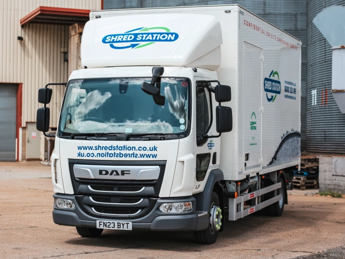 A Shred Station branded on-site shredding vehicle, parked in front of grain silos.