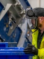 Shred Station operative pushing large blue waste bin in full PPE.