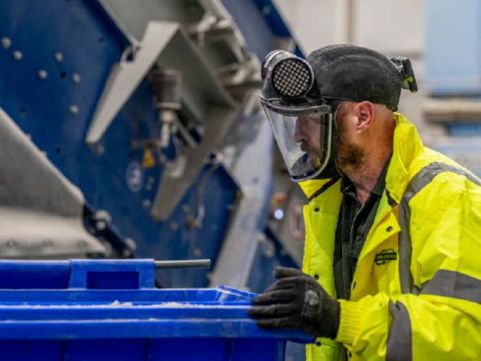 Shred Station operative pushing large blue waste bin in full PPE.