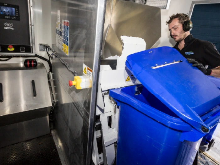 Shred Station operative emptying confidential waste into a shredder.