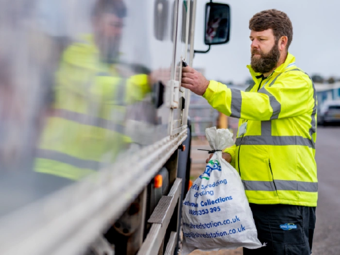 Shred Station operative carrying cable-tied bag of confidential waste paper.
