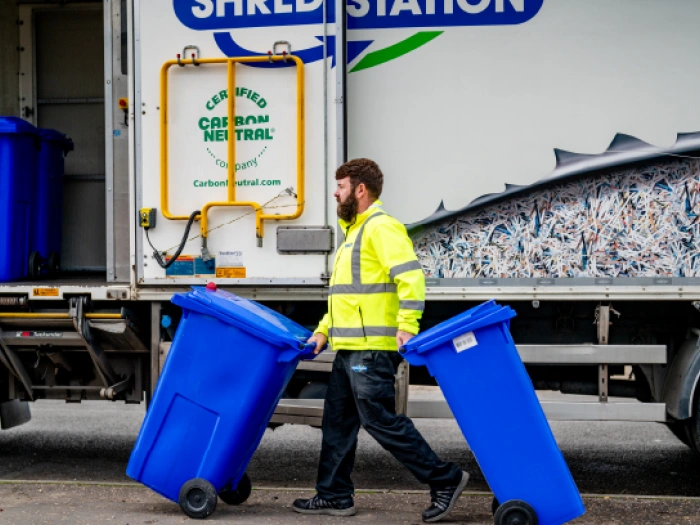 Shred Station employee wheeling two confidential waste bins.