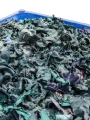 Plastic dolav box of shredded blue and green textile uniforms.