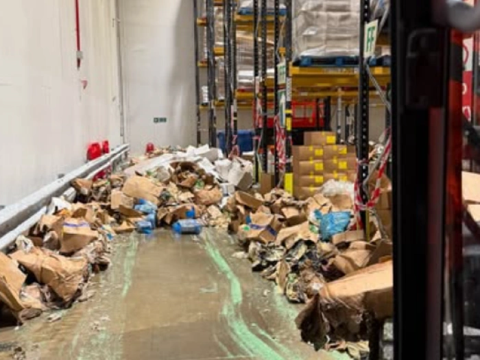 A warehouse floor with hundreds of spilled and crushed cardboard boxes.