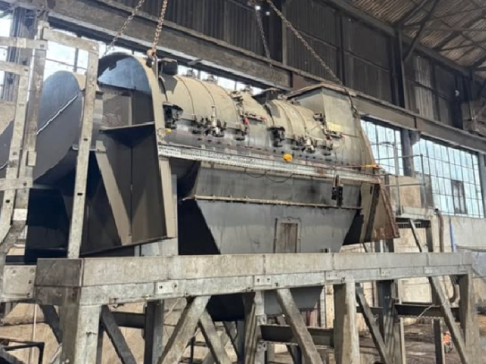 Large piece of machinery being removed from warehouse with chain lift.