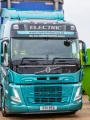 Electric articulated truck next to two skip containers.