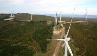 Wind turbines set on forested hills from aerial view.