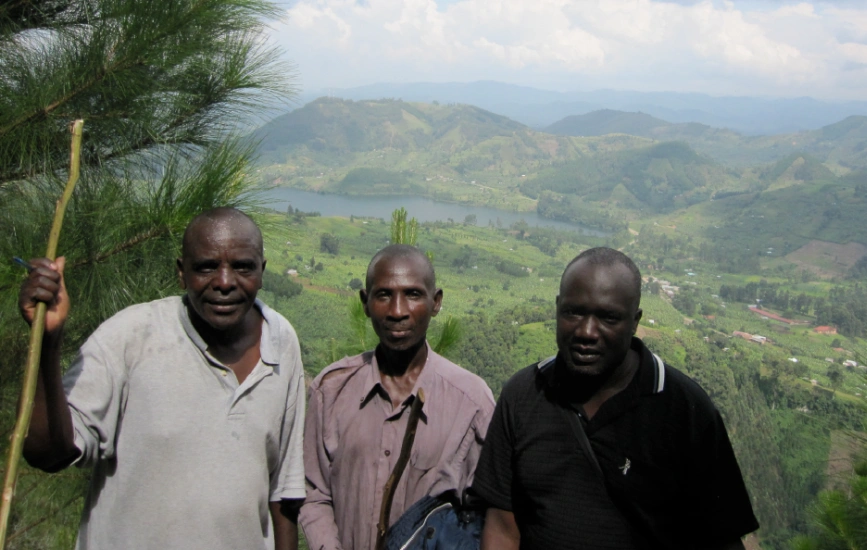 Three men standing on hilltop. Members of the local community on project land in the Uganda Community Reforestation Project.