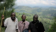 Three men standing on hilltop. Members of the local community on project land in the Uganda Community Reforestation Project.