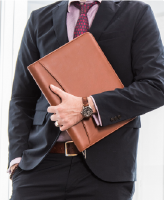 Man holding brown leather folder close to their chest