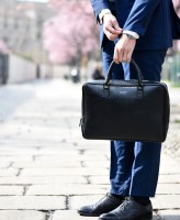 Image of midsection of person in suit holding a briefcase