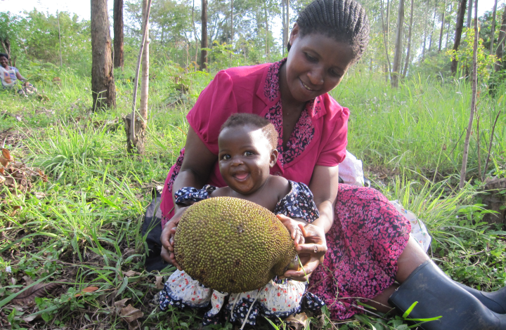 Image of smiling Ugandan mother and her laughing baby daughter while collecting fruit