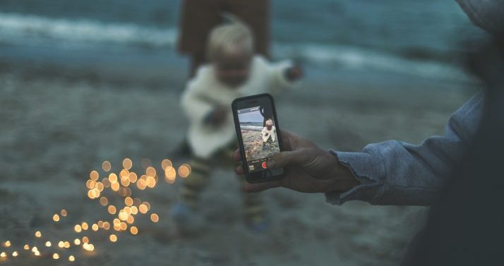 Image of person taking video of their child through a phone screen