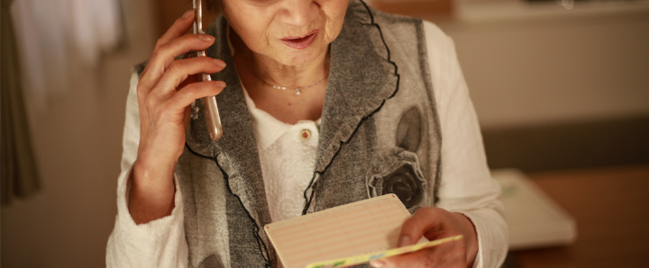 Person looking concerned whilst talking on the phone and opening a letter