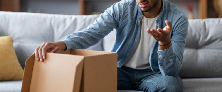 Image of person looking confused whilst opening parcel