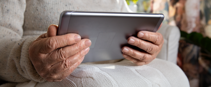 Image of old hands holding a digital tablet